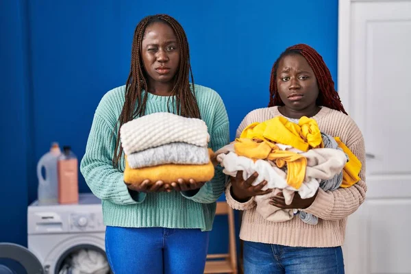 Dos Mujeres Africanas Sosteniendo Ropa Doblada Después Planchar Escéptico Nervioso — Foto de Stock