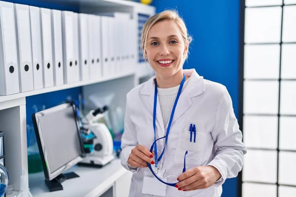 Young Blonde Woman Scientist Smiling Confident Holding Glasses Laboratory — Stock Photo, Image
