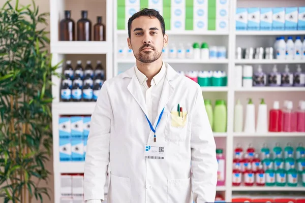 Handsome Hispanic Man Working Pharmacy Drugstore Relaxed Serious Expression Face — Zdjęcie stockowe