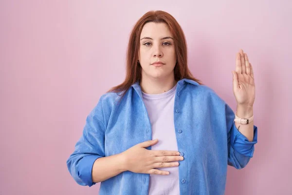 Young Hispanic Woman Red Hair Standing Pink Background Swearing Hand — Stockfoto