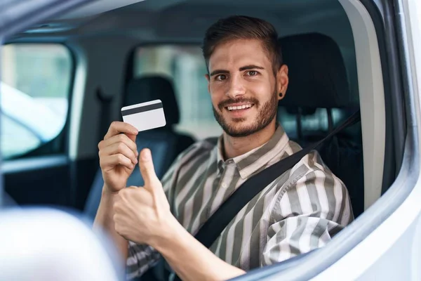 大胡子的西班牙裔男子开着汽车 手里拿着信用卡 喜形于色 大手大脚地做着出色的事 签了字 — 图库照片