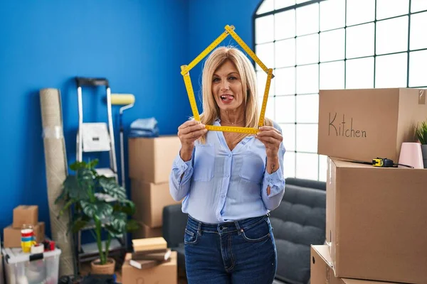 Middle Age Blonde Woman Moving New Home Sticking Tongue Out — Stockfoto