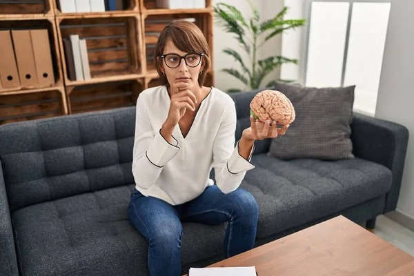 Brunette Woman Working Therapy Office Holding Brain Serious Face Thinking — Foto de Stock