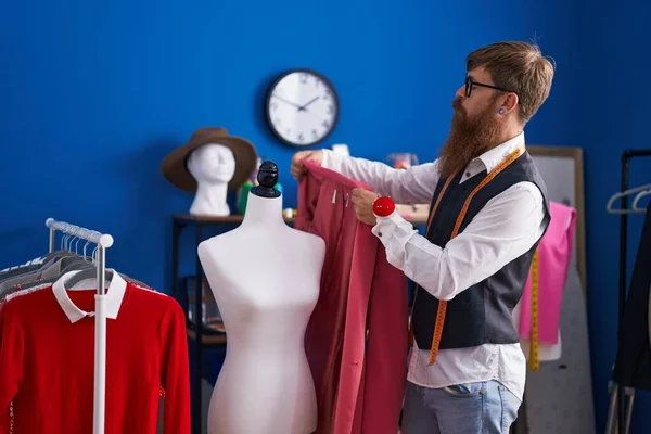 红头发的年轻人裁缝师在服装厂拿着夹克 — 图库照片
