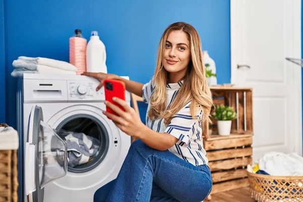 Ung Blond Kvinna Använder Smartphone Och Tvätta Kläder Tvättstuga — Stockfoto