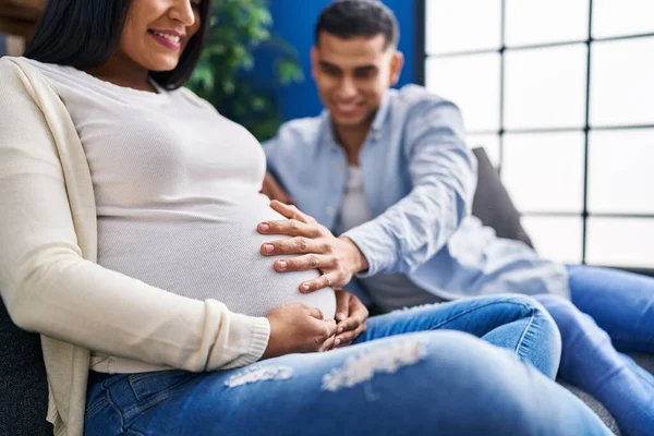 Unga Latinska Par Förväntar Baby Vidröra Magen Sitter Soffan Hemma — Stockfoto