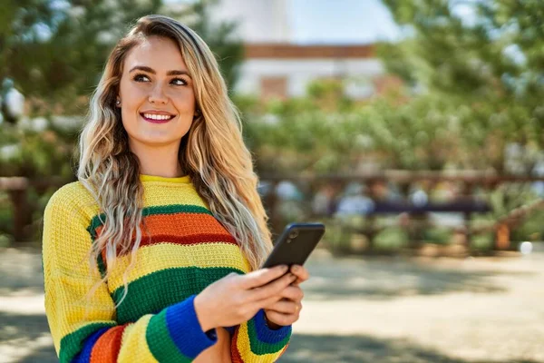 stock image Young blonde woman using smartphone at the park