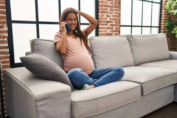 Young pregnant woman having conversation speaking on the smartphone stressed and frustrated with hand on head, surprised and angry face