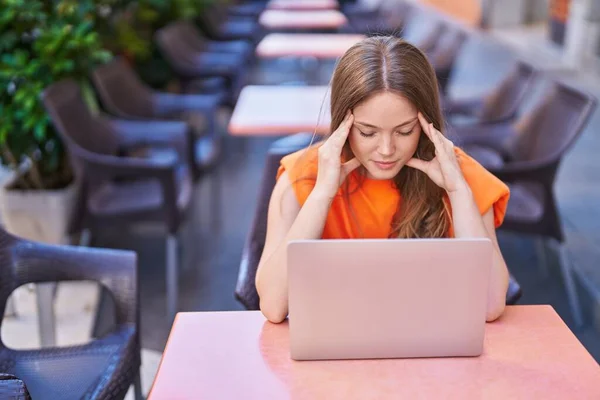 年轻女人强调要使用笔记本电脑 坐在咖啡店阳台的桌子上 — 图库照片