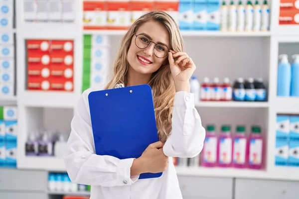 Joven Farmacéutica Sonriendo Confiada Sujetando Portapapeles Farmacia —  Fotos de Stock