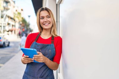 Genç İspanyol kadın mağaza asistanı sokakta dokunmatik ped kullanıyor.