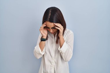 Young hispanic woman standing over white background with sad expression covering face with hands while crying. depression concept. 