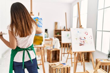 Middle age hispanic woman on back view drawing at art studio