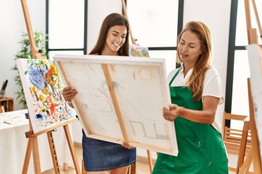 Anne ve kızı gülümsüyor. Sanat stüdyosunda kendine güvenen bir tablo çiziyor.
