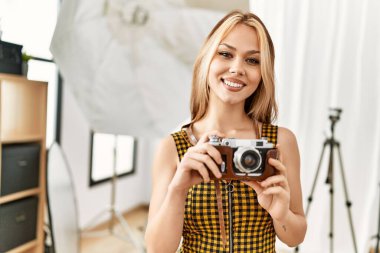 Beyaz kadın fotoğrafçı elinde klasik fotoğraf stüdyosu tutuyor.