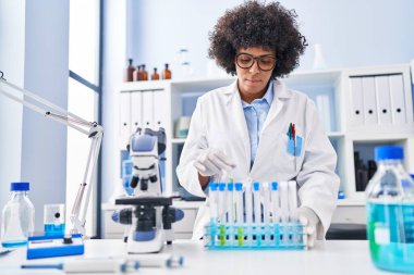 Laboratuvarda test tüpleri tutan Afrikalı Amerikalı kadın bilim adamı.