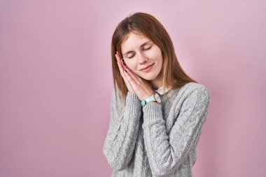 Güzel bir kadın pembe arka planda ayakta uyur, yorgun düşler görür ve elleri ile poz verir, gözleri kapalı gülümserdi.. 