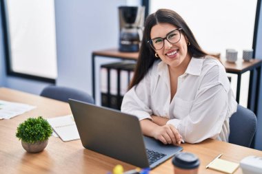 Ofiste çalışan genç İspanyol iş kadını laptopu kullanıyor.