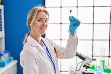 Laboratuvarda test tüpü tutan genç sarışın bilim kadını.