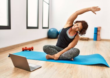 Orta yaşlı İspanyol sporcu kadın spor merkezinde online fitness dersi alıyor..