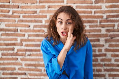 Güzel esmer kadın tuğlaların üzerinde duruyor. Duvar dudak dudağa. Gizli dedikodular söylüyor, kötü niyetli konuşmalar fısıldıyor. 