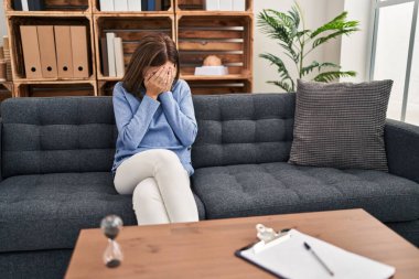 Muayenehanedeki genç esmer kadın. Ağlarken yüzünü ellerle kapatan üzgün bir ifadeyle. depresyon kavramı. 