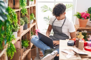 Çiçekçide dizüstü bilgisayar kullanan genç İspanyol bir çiçekçi.