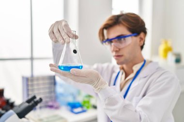 Young caucasian man scientist looking test tube at laboratory