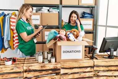 Yardım merkezinde çalışmaktan mutlu gülümseyen iki genç gönüllü kadın. Gülümseyen mutlu bir kız akıllı telefonda konuşuyor..