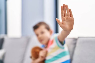 Sarışın çocuk evde el hareketlerini durduruyor.