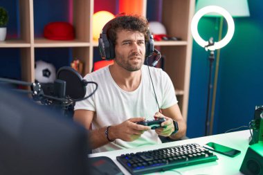 Genç İspanyol asıllı adam müzik stüdyosunda joystick kullanarak video oyunu oynuyor.