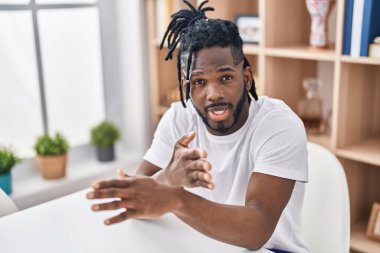 Afrika kökenli Amerikalı bir kadın evde masada oturuyor.
