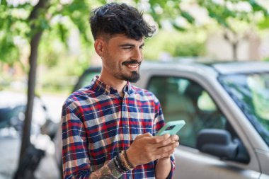 Sokakta akıllı telefon kullanan, kendine güvenen genç bir İspanyol.