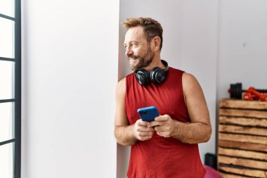 Orta yaşlı İspanyol bir adam spor merkezinde akıllı telefon kullanıyor.