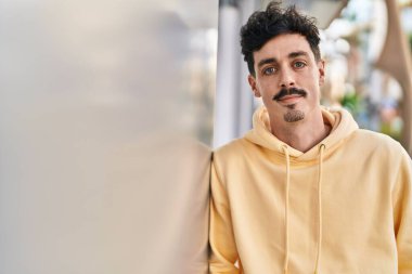 Sokakta ciddi bir ifadeyle duran beyaz bir genç.