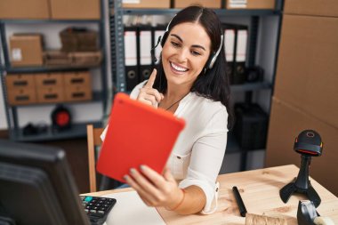 Küçük işletmelerde çalışan Latin kökenli genç bir kadın video konuşmasında gülümseyen mutlu bir şekilde el ve parmak işareti yapıyor. 