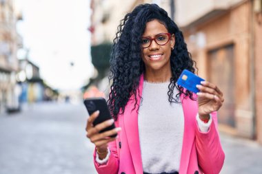 Sokakta akıllı telefon ve kredi kartı kullanan Afrikalı Amerikalı kadın yönetici.