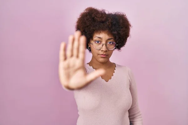 ピンクの背景に立っている若いアフリカ系アメリカ人の女性は 手の手のひらで歌うのをやめます 顔に負の重大なジェスチャーで — ストック写真