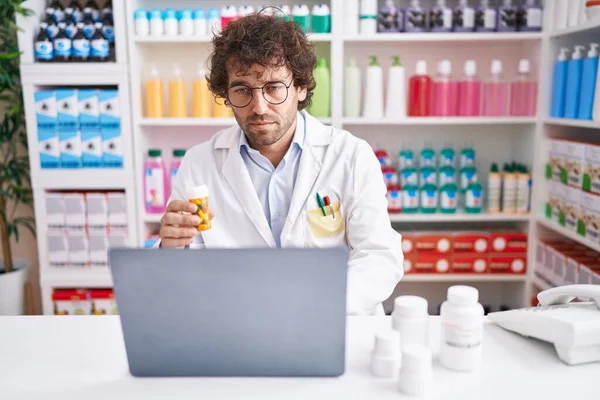 Молодий Іспаномовний Чоловік Фармацевт Використовує Ноутбук Тримає Пляшку Таблеток Аптеці — стокове фото