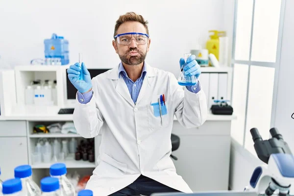 化学製品を抱える科学研究所で働く中年男性は 頬に面白い顔をしています 空気を吸い込み空気を吸い込み — ストック写真