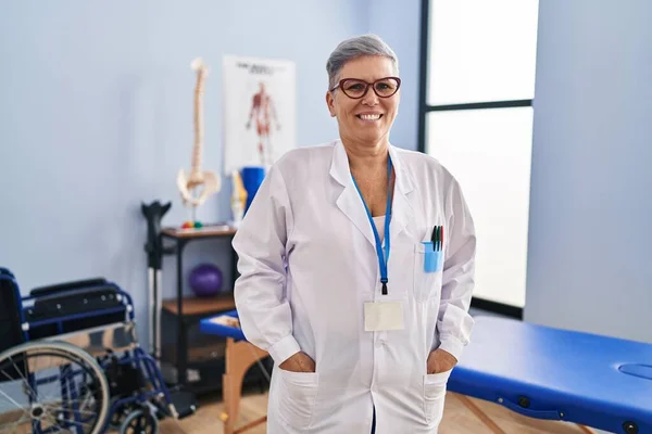 Fisioterapeuta Mujer Mediana Edad Sonriendo Confiada Pie Clínica Rehabilitación —  Fotos de Stock