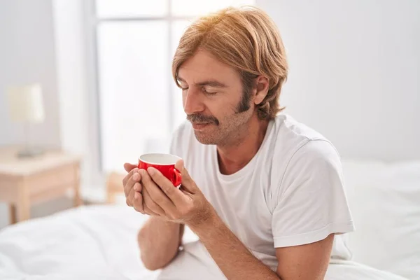 Νεαρός Ξανθός Άντρας Πίνει Καφέ Καθισμένος Στο Κρεβάτι Στην Κρεβατοκάμαρα — Φωτογραφία Αρχείου