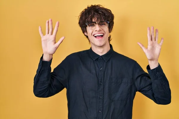 Молодий Чоловік Носить Окуляри Жовтому Фоні Показуючи Вказуючи Пальцями Номер — стокове фото