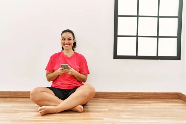 Νεαρή Όμορφη Ισπανόφωνη Γυναίκα Χρησιμοποιώντας Smartphone Κάθεται Στο Πάτωμα Άδειο — Φωτογραφία Αρχείου