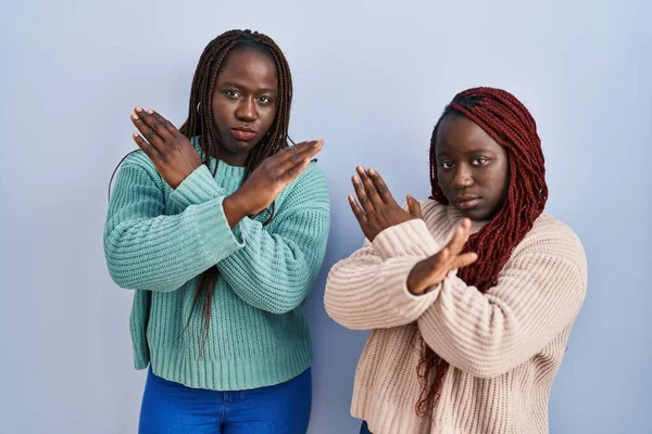 两个非洲女人站在蓝色背景下 拒绝表情交叉双臂做着消极手势 生气的脸 — 图库照片
