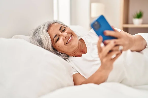 Μεσήλικη Γυναίκα Που Χρησιμοποιεί Smartphone Ξαπλωμένη Στο Κρεβάτι Στο Υπνοδωμάτιο — Φωτογραφία Αρχείου