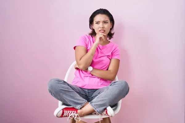 Hispanic Young Woman Sitting Chair Pink Background Thinking Worried Question — Zdjęcie stockowe