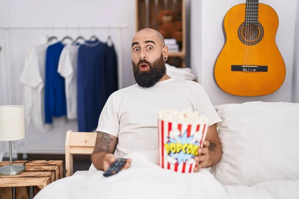 Young Hispanic Man Beard Tattoos Eating Popcorn Bed Afraid Shocked — Stock Photo, Image