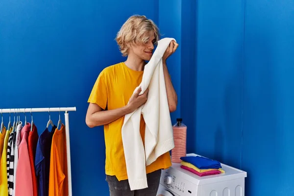 Young Blond Man Smiling Confident Smelling Clothes Laundry Room — ストック写真