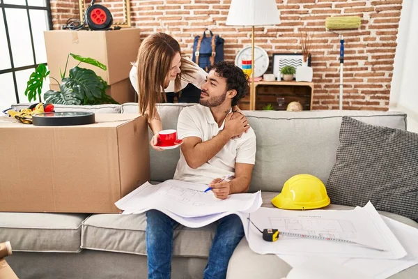 Man and woman couple drinking coffee looking house plans at new home